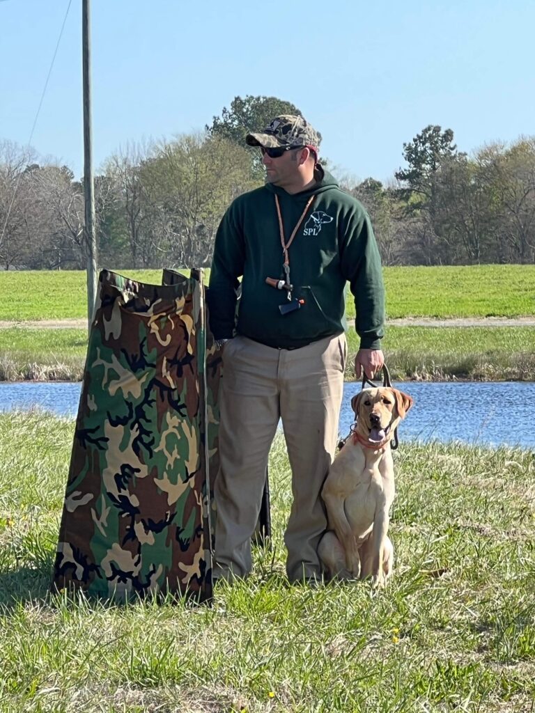 A man and his dog are standing in the grass.