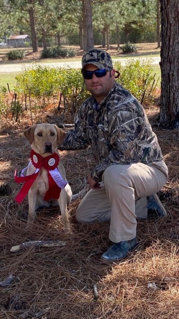 A man kneeling down next to a dog.